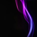 Abstract purple smoke on a black background, capturing motion and glow.