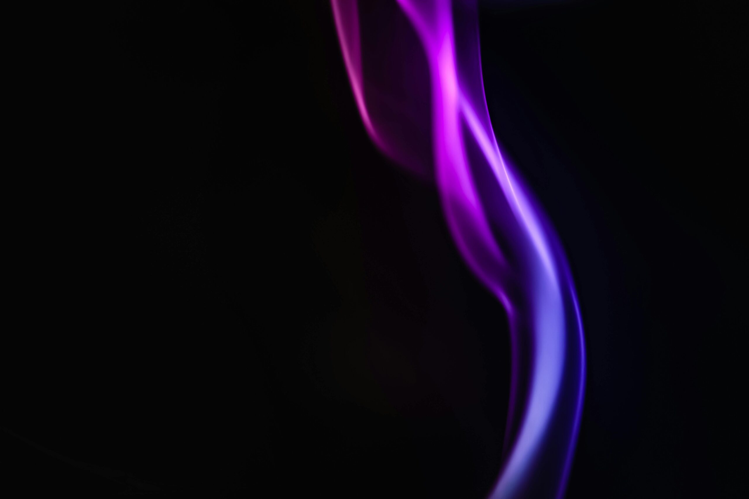 Abstract purple smoke on a black background, capturing motion and glow.